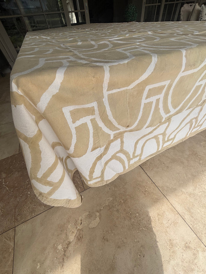 Eclectic 100% cotton tablecloth in sand and white with a bold abstract pattern draped over a large dining table