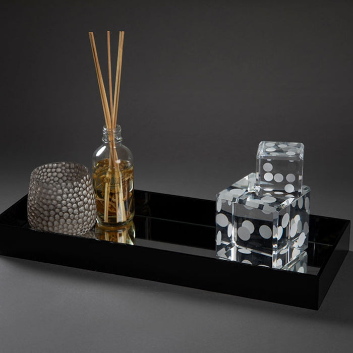 Eclectic black acrylic mirrored display tray holding a reed diffuser and decorative dice on a dark background.
