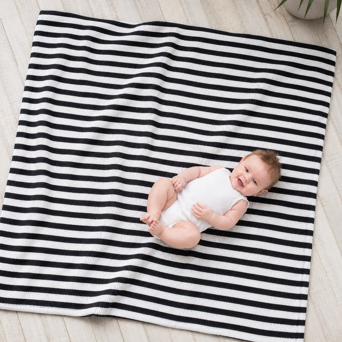 Eclectic Aden + Anais black and white striped muslin cotton swaddle blanket with a baby lying on it