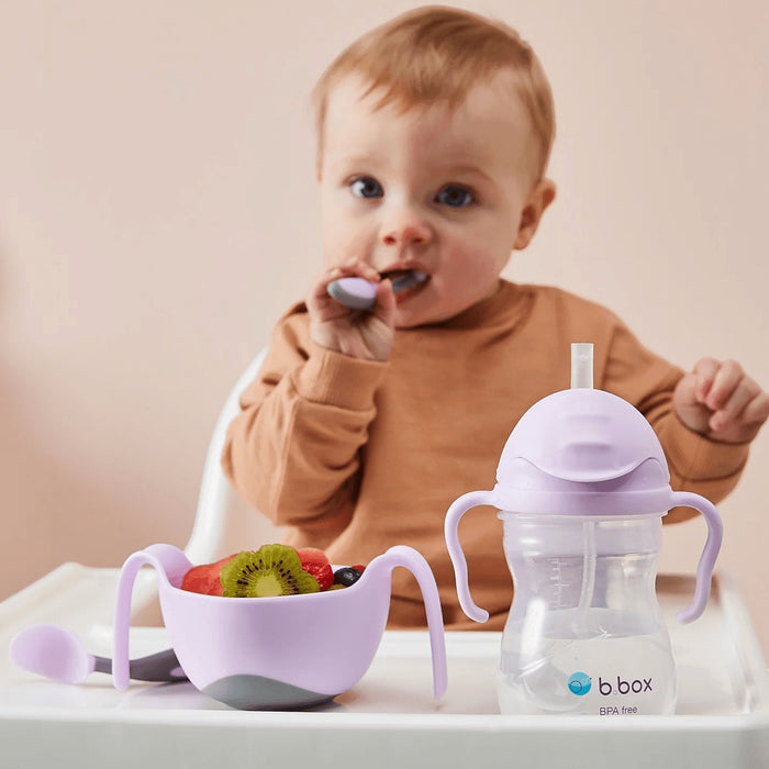 Eclectic b.box boysenberry sippy cup and bowl set with a toddler eating fruit in a high chair