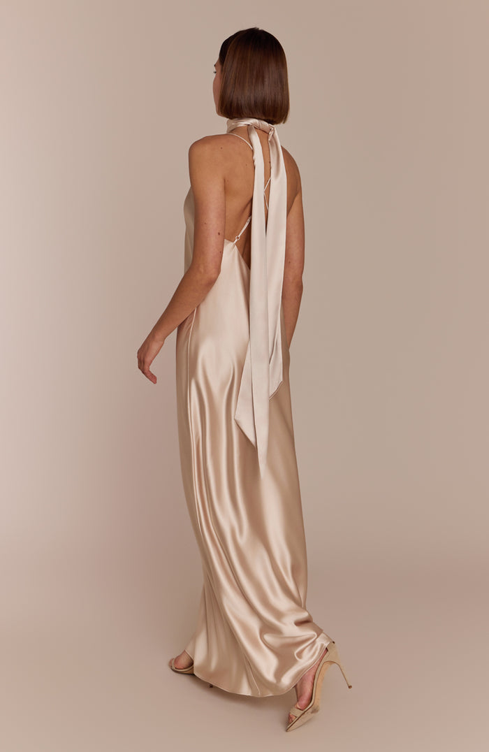 Woman wearing a beige satin dress with a sheer scarf on a beige background