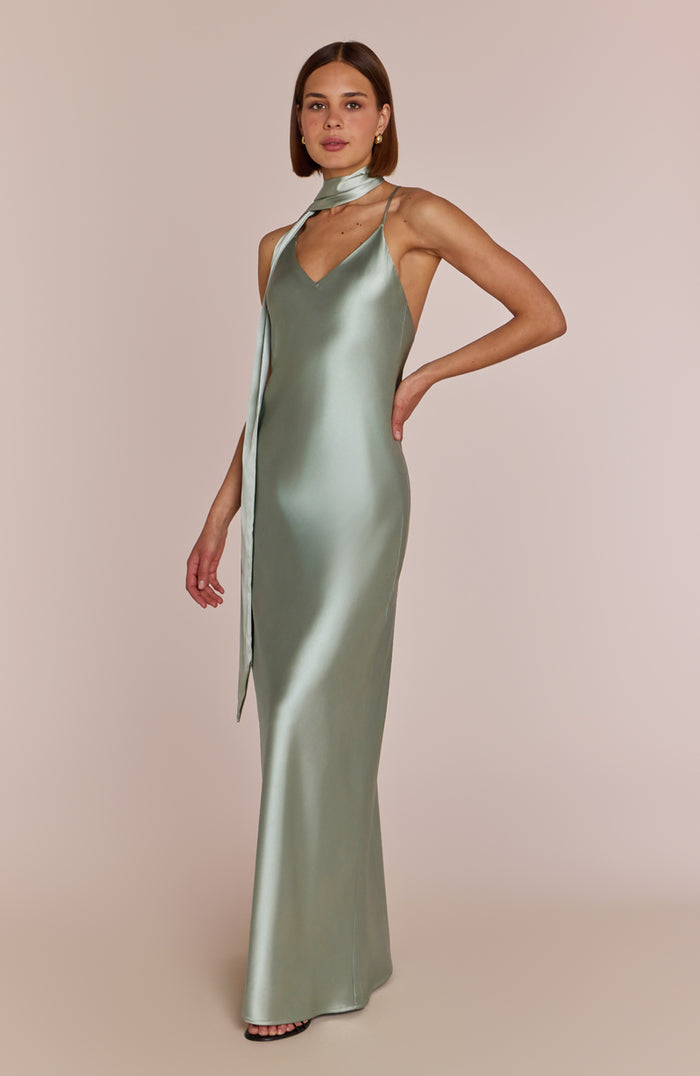 Woman wearing a green satin gown against a beige background