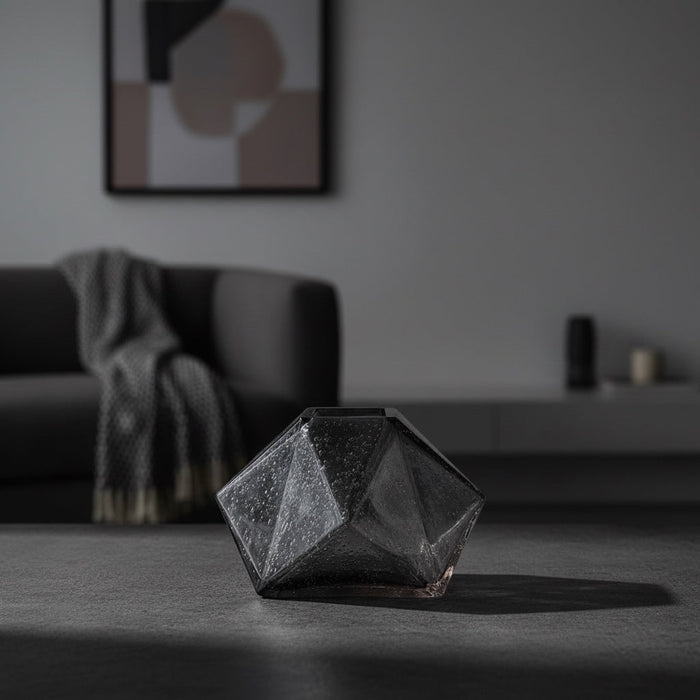 Eclectic charcoal diamond glass vase with a faceted geometric design on a dark surface in a modern living room.