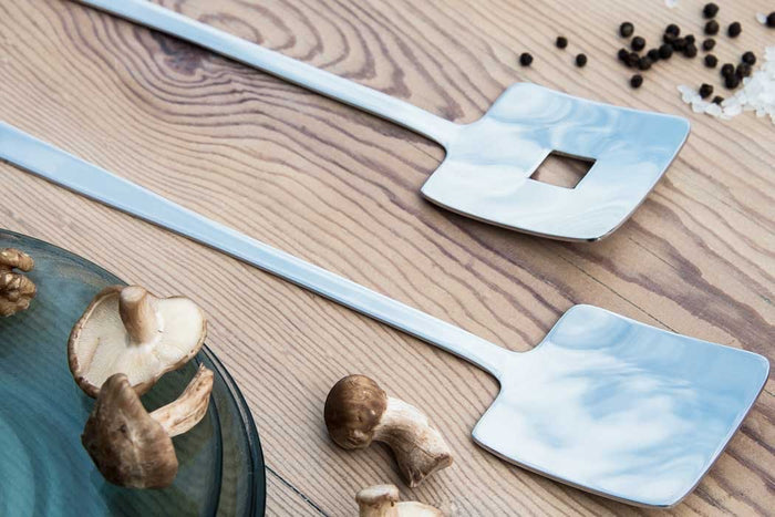 Eclectic Deco geometric salad servers in polished stainless steel with square cutout detail on a wooden table