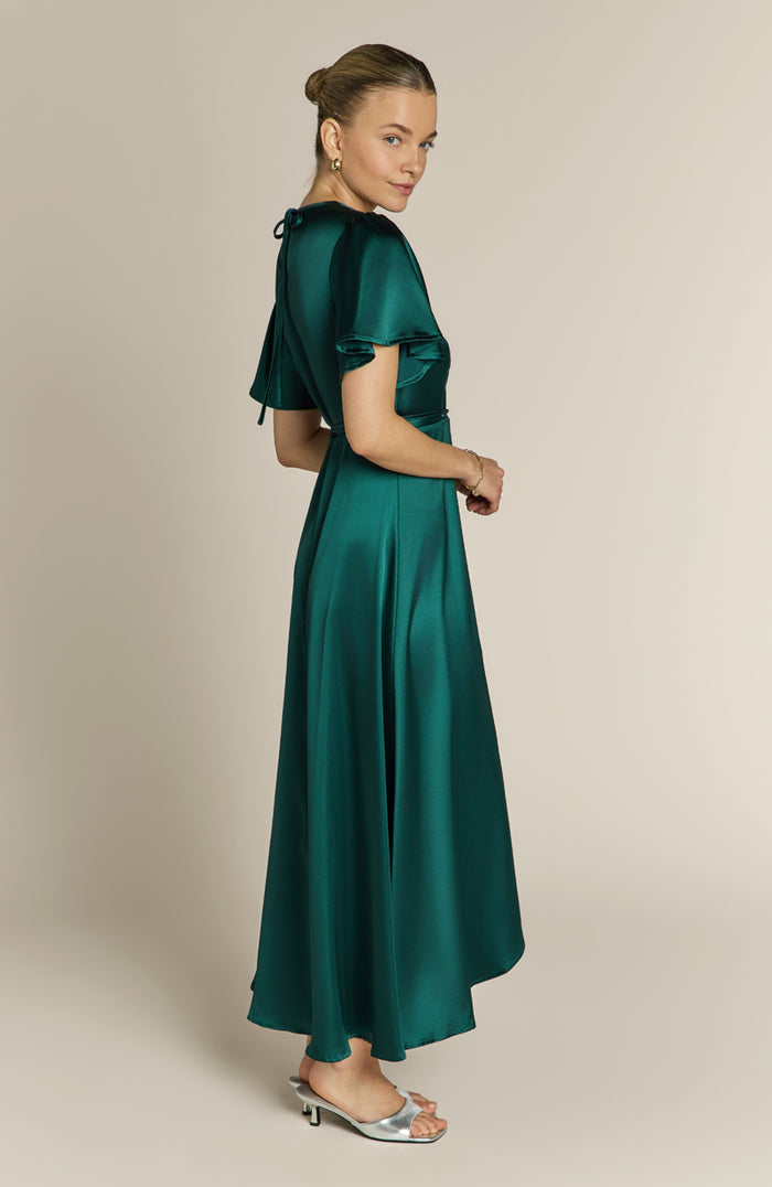 Woman wearing a green satin dress against a beige background
