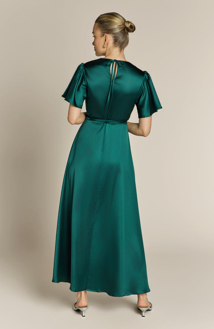 Woman wearing a green dress with short sleeves and a belt on a beige background