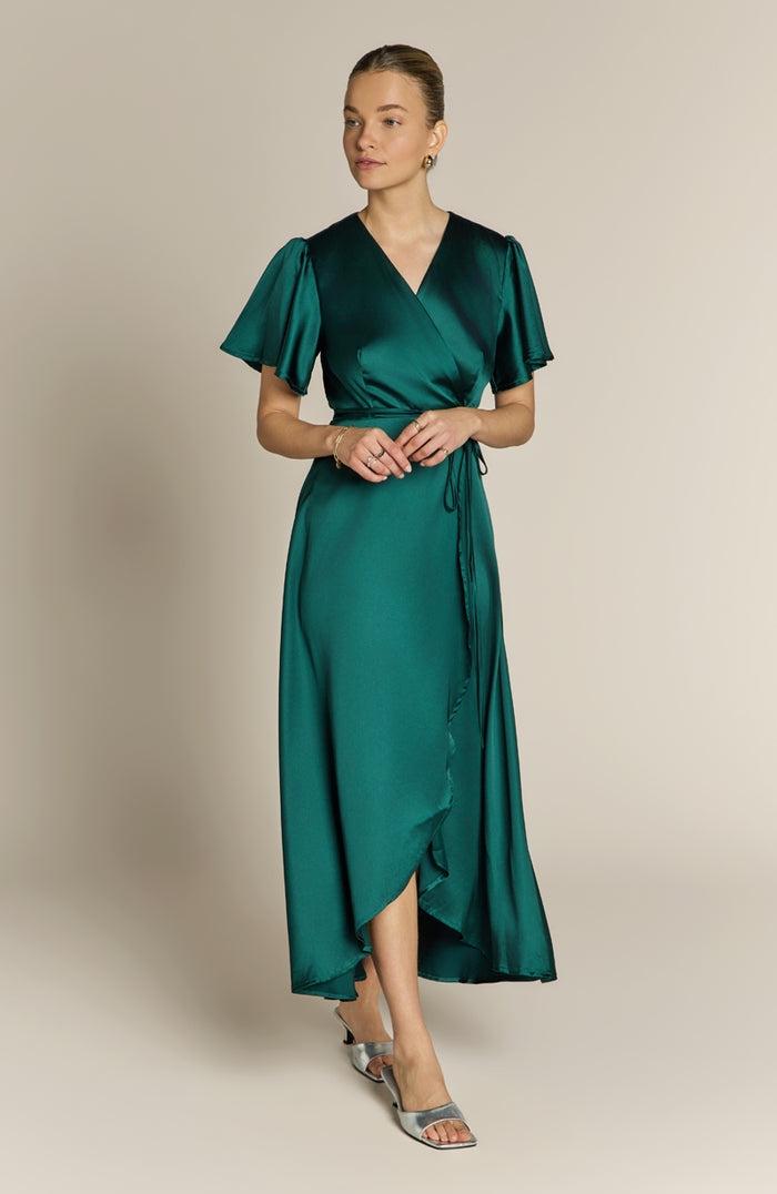 Woman wearing a green dress against a beige background