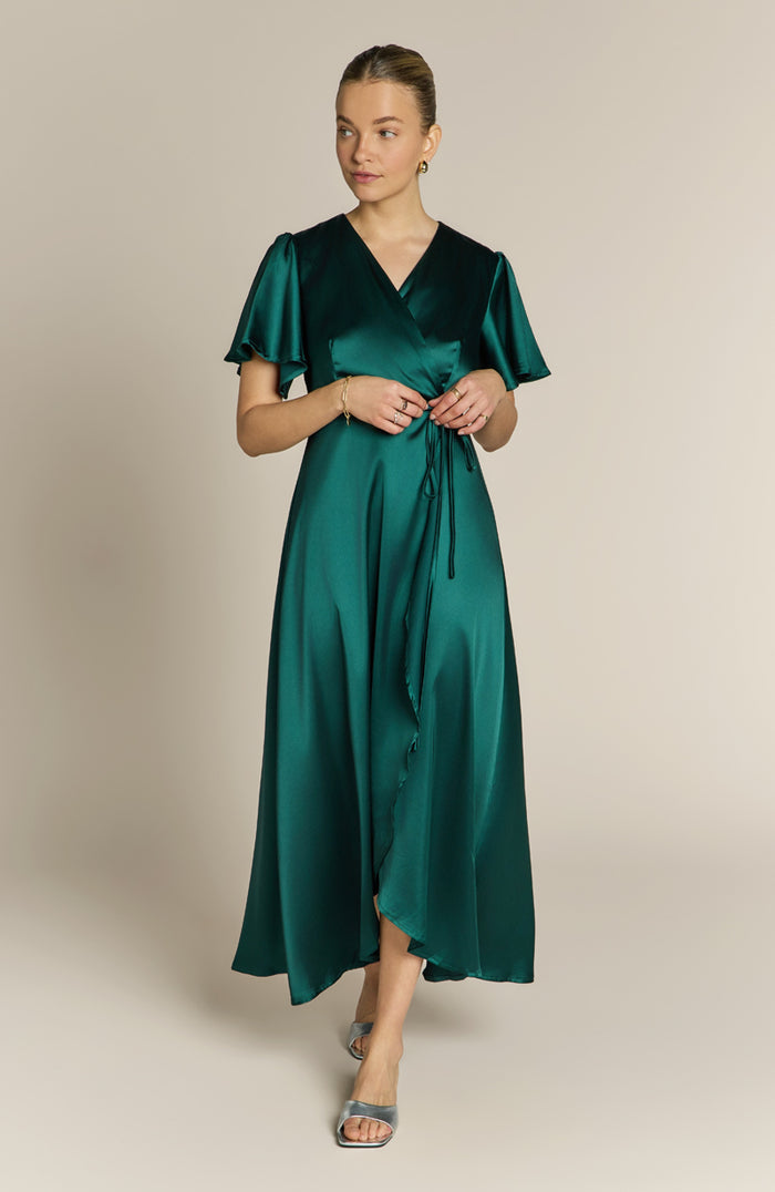 Woman wearing a green satin dress against a beige background