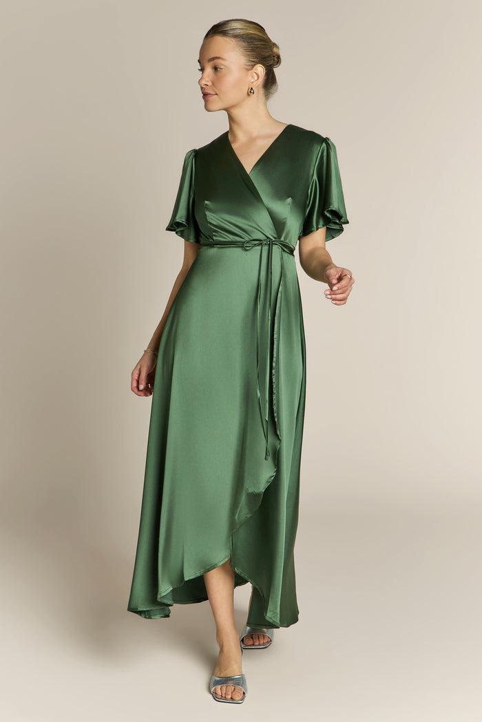 Woman wearing a green satin dress against a beige background