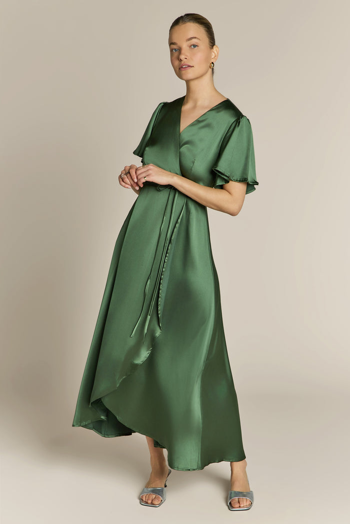 Woman wearing a green satin wrap dress against a beige background