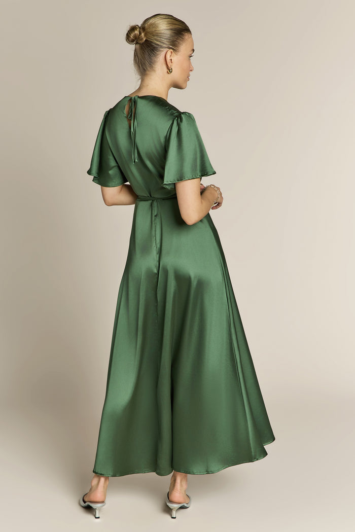 Woman wearing a green wrap dress against a beige background