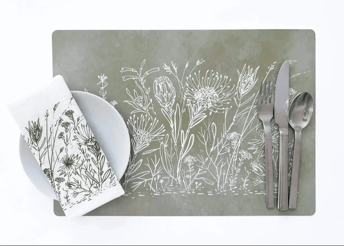 Eclectic sage green reusable placemat with white botanical fynbos illustration, set with cutlery and a matching napkin.