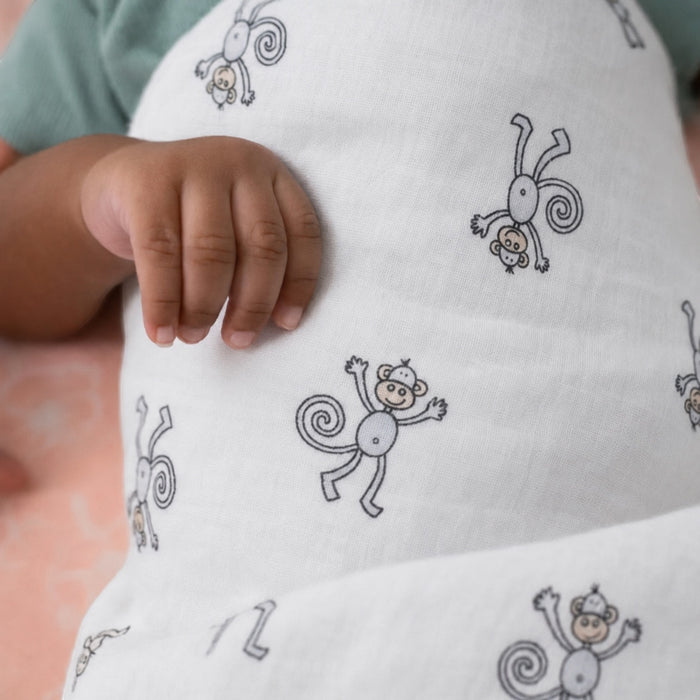 Eclectic Aden + Anais Jungle Jam muslin swaddle blanket with monkey print wrapped around a baby's hand