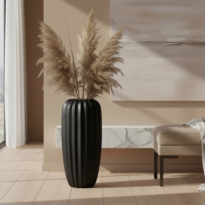 Eclectic 50cm matte black fluted fibrestone vase styled with tall dried grass in a modern neutral living room.