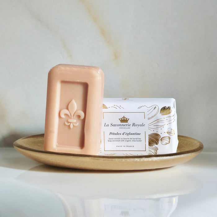 Eclectic La Savonnerie Royale Petales d'Eglantine soap bar with fleur-de-lys embossing on a gold dish.