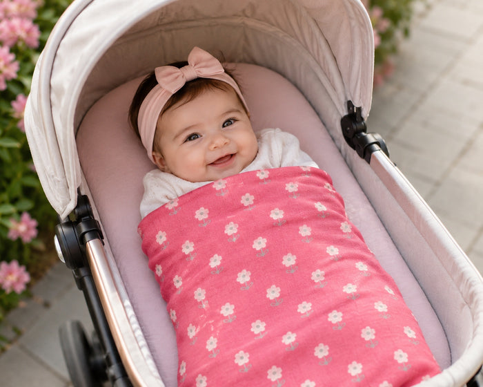 Eclectic baby girl smiling in a pram wrapped in a soft pink blossom print cotton flannel blanket