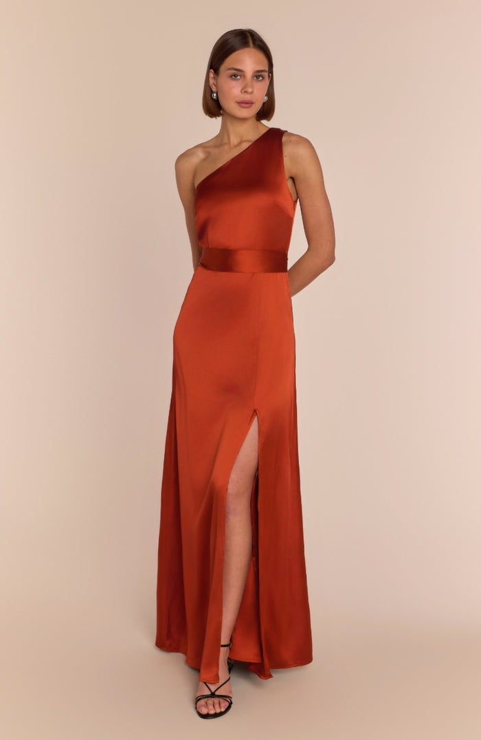 Woman wearing a one-shoulder red dress with a slit on a beige background
