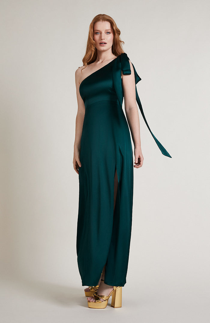 Woman wearing a green one-shoulder dress with a ribbon on a plain background