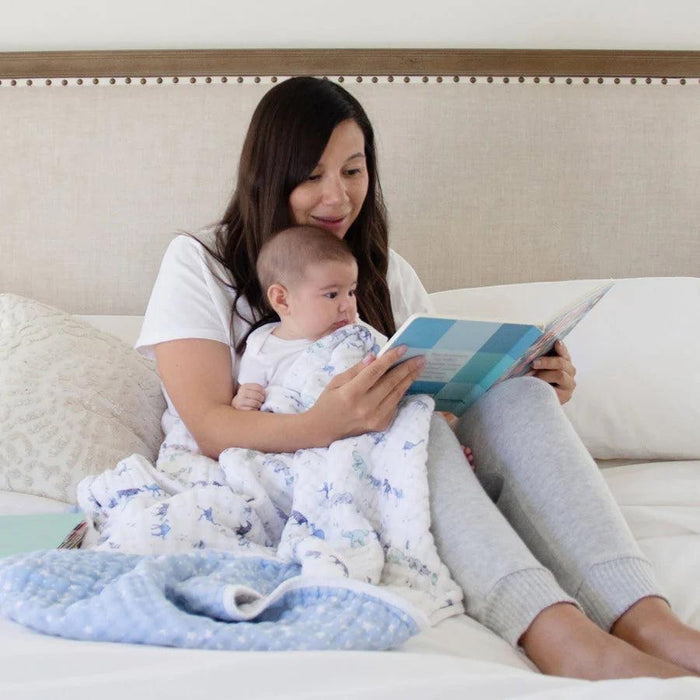 Eclectic Aden + Anais Rising Star cotton muslin dream blanket draped over a mother and baby reading a book in bed