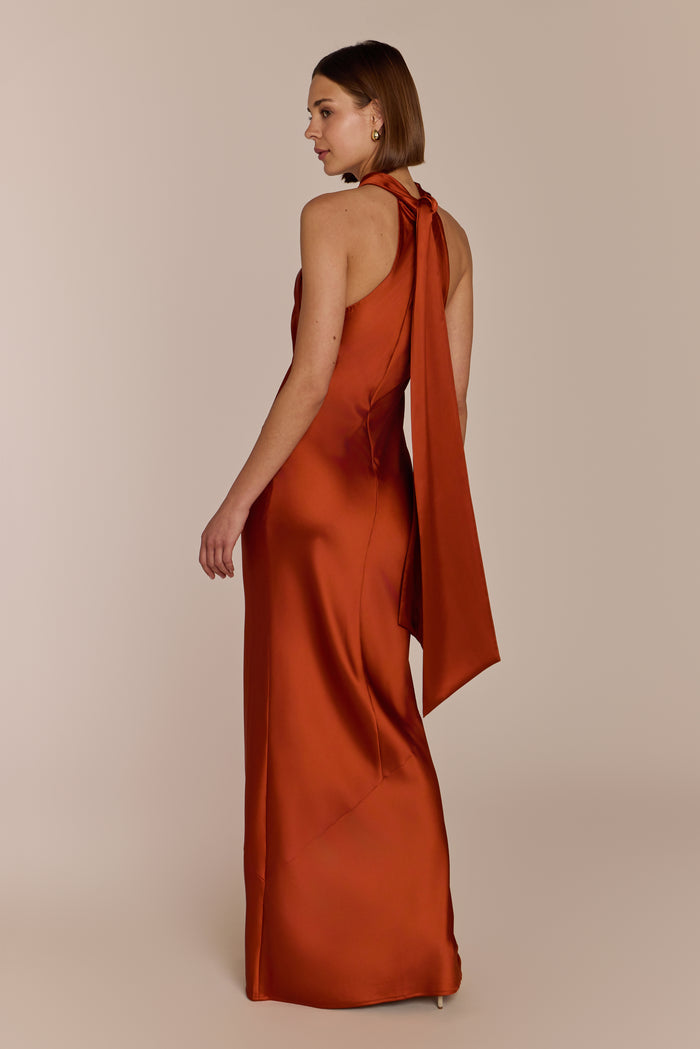 Side view of burnt orange Roma dress showing bias cut drape and floor-length silhouette