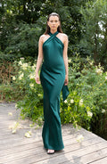Woman in a green dress standing on a wooden deck with greenery in the background