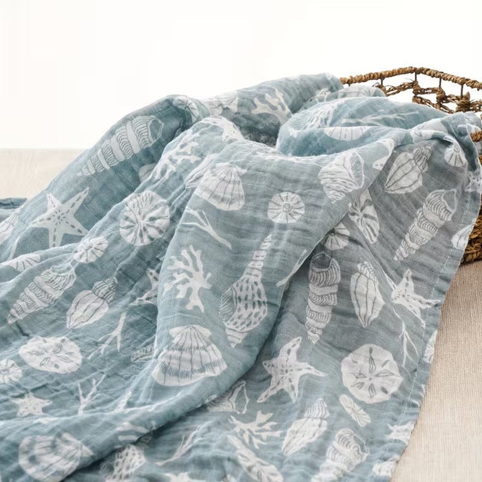 Eclectic Seaside Shells cotton muslin swaddle in seafoam green with white coastal shell print, soft and breathable.