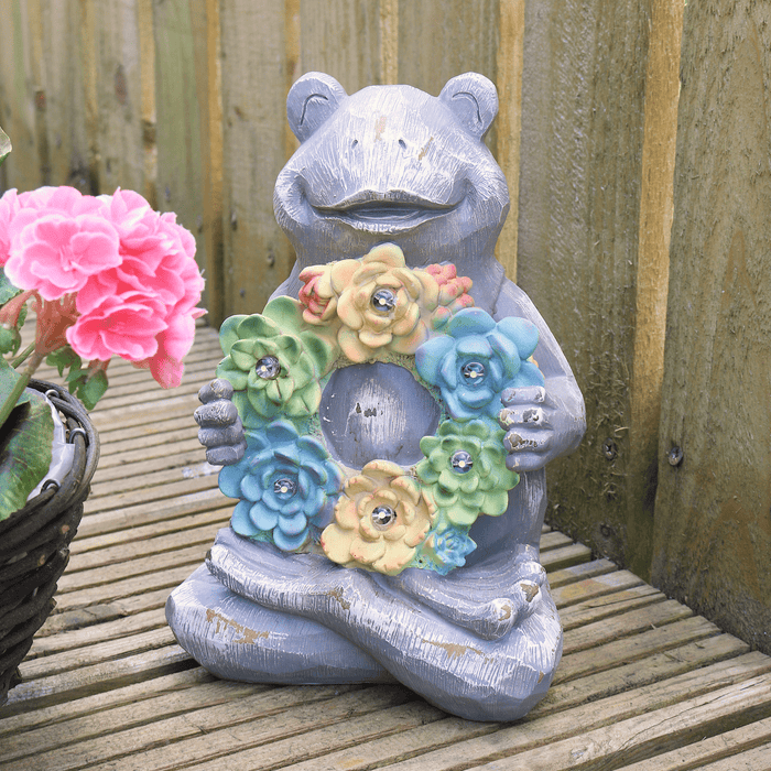 frog solar ornament on patio space beside pink flowers