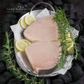 Two raw swordfish steaks on a metal plate with rosemary and lemon