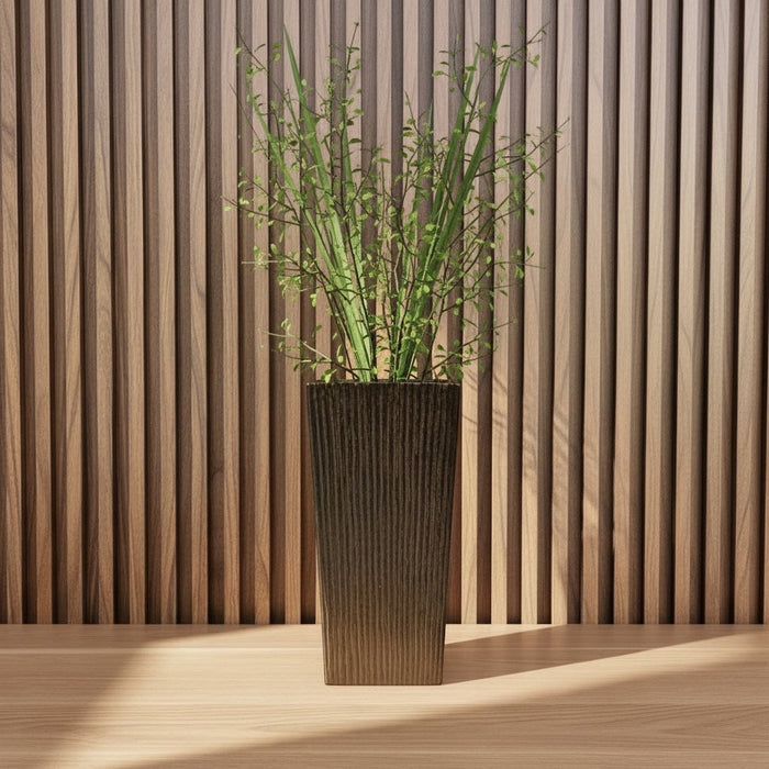 Eclectic earth brown ceramic floor vase with vertical ribbed texture holding tall green stems against a wood slat wall