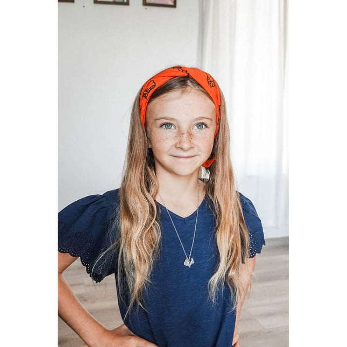 Young girl wearing an orange headband indoors