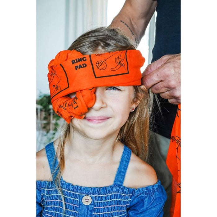 Child wearing an orange bandana over one eye with a person adjusting it.