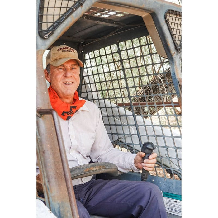 Man sitting inside a rugged vehicle wearing a cap and bandana around his neck.