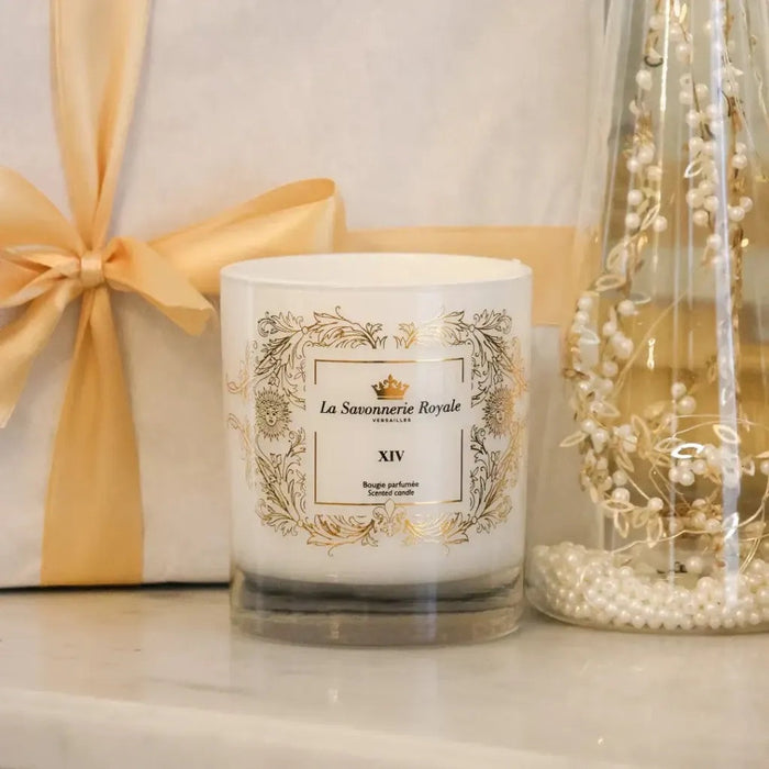 Eclectic La Savonnerie Royale XIV scented candle in a white glass vessel with ornate gold detailing on a marble surface