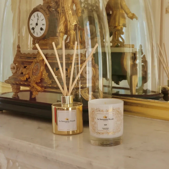 Eclectic La Savonnerie Royale XIV candle and reed diffuser set in a decorative glass vessel on a marble mantelpiece.